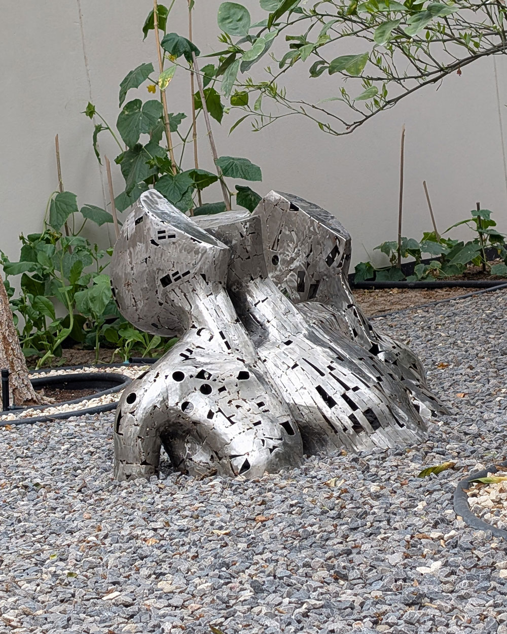 Abstract stainless steel sculpture in outdoor garden setting